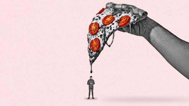 A man stand below a giant slice of pizza while looking down at his phone