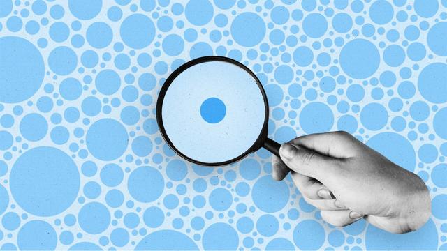 hand holding a magnifying glass looks at one circle while many circles appear outside the magnifying glass.