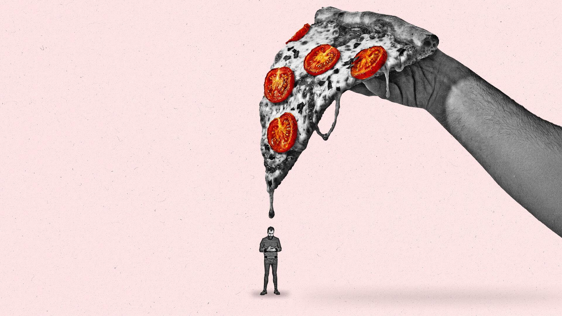 A man stand below a giant slice of pizza while looking down at his phone