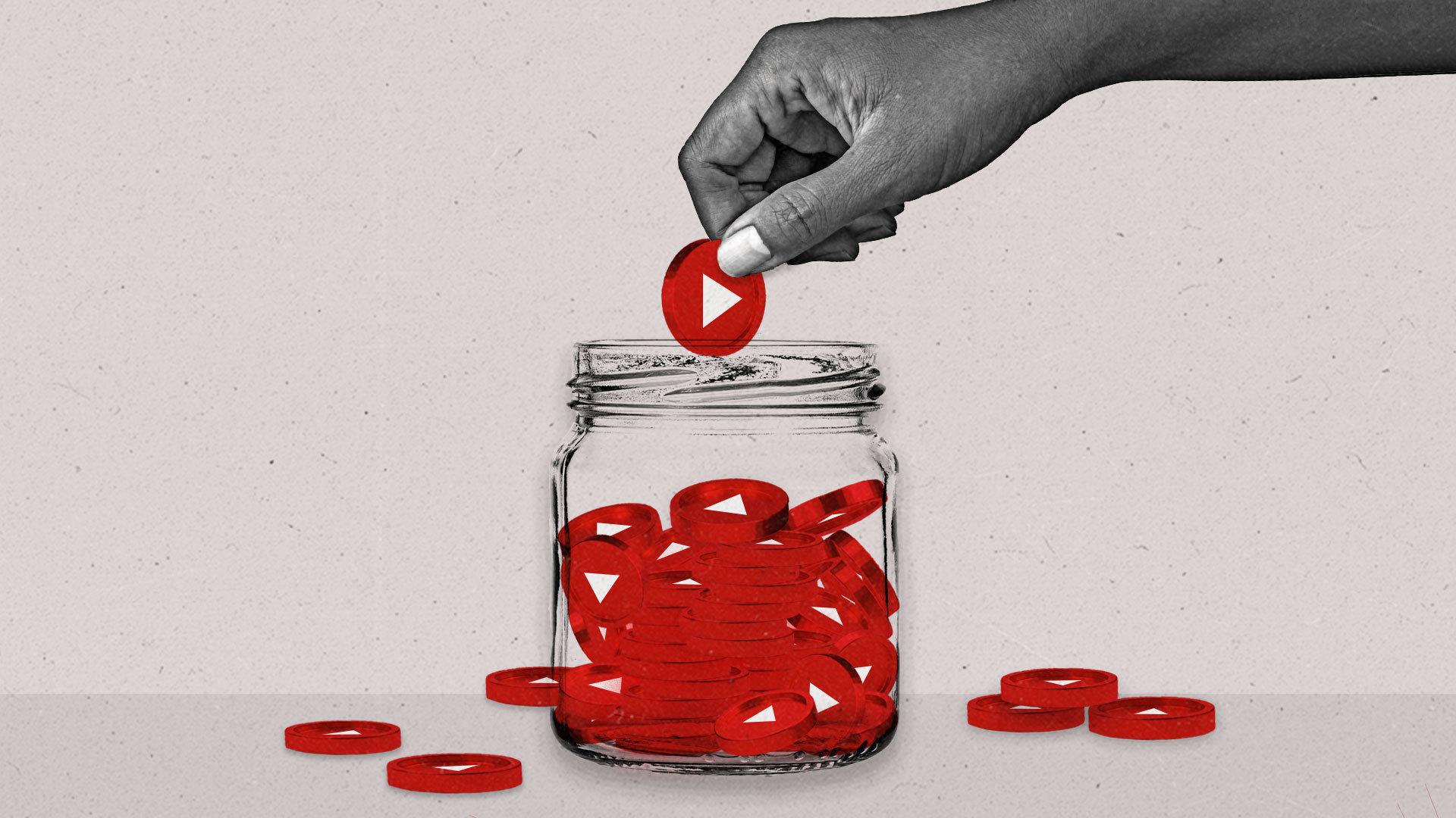 A hand places a red coin with a play button on it into a jar full of similar coins. A few coins surround the jar on the floor as well.