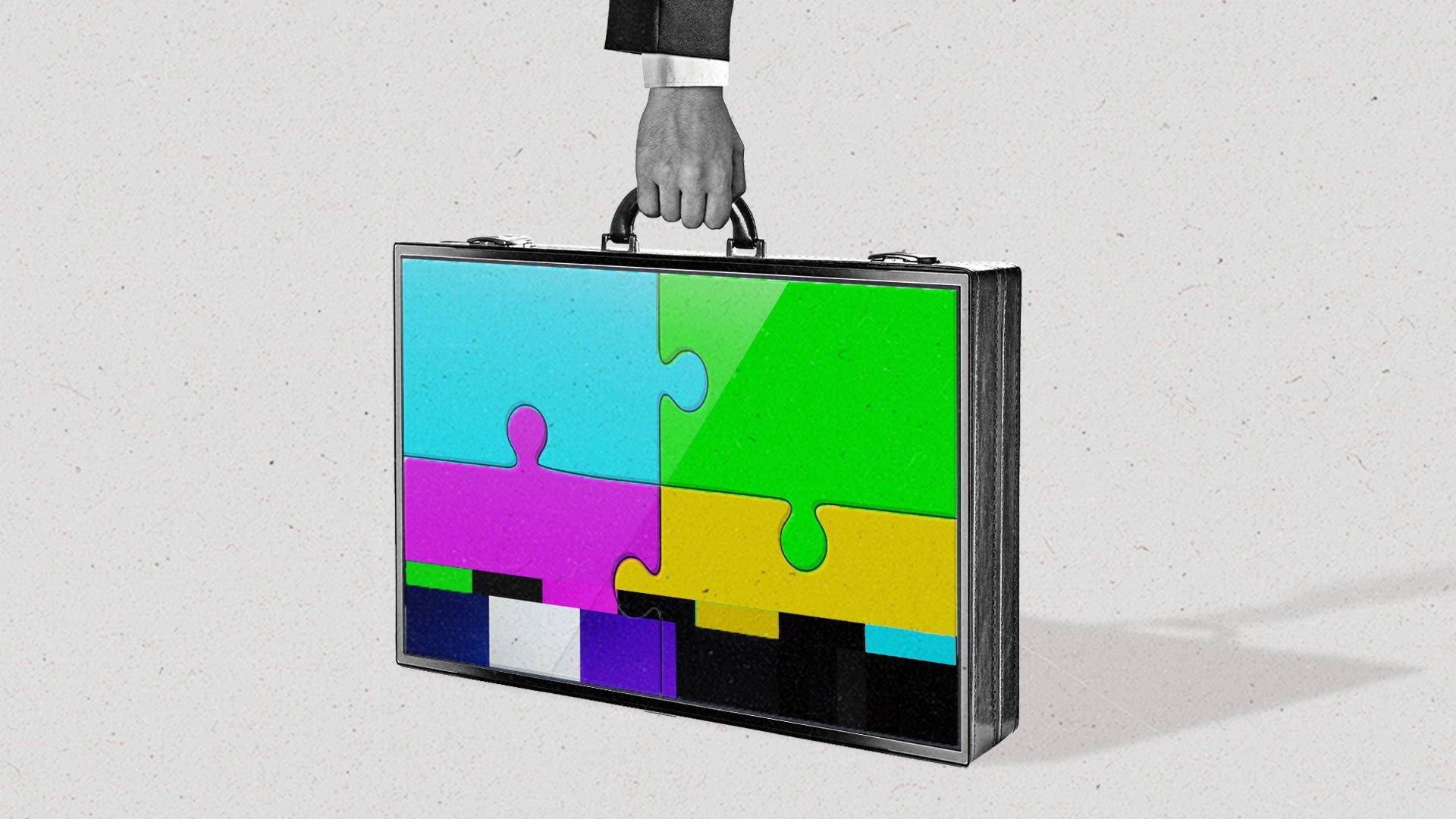 A man lifts the handle on a briefcase made from a connected TV, which shows a puzzle piece test pattern on the screen.
