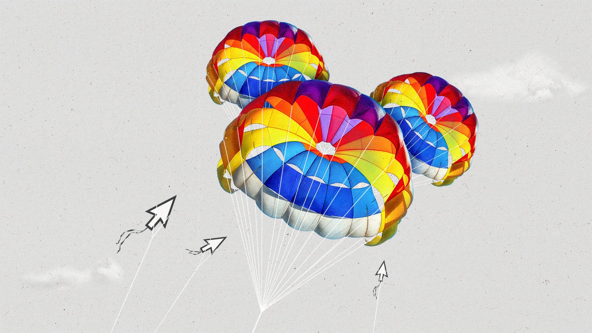 A Disney Mickey-shaped rainbow kite flies in the sky above three smaller cursor-shaped kites.