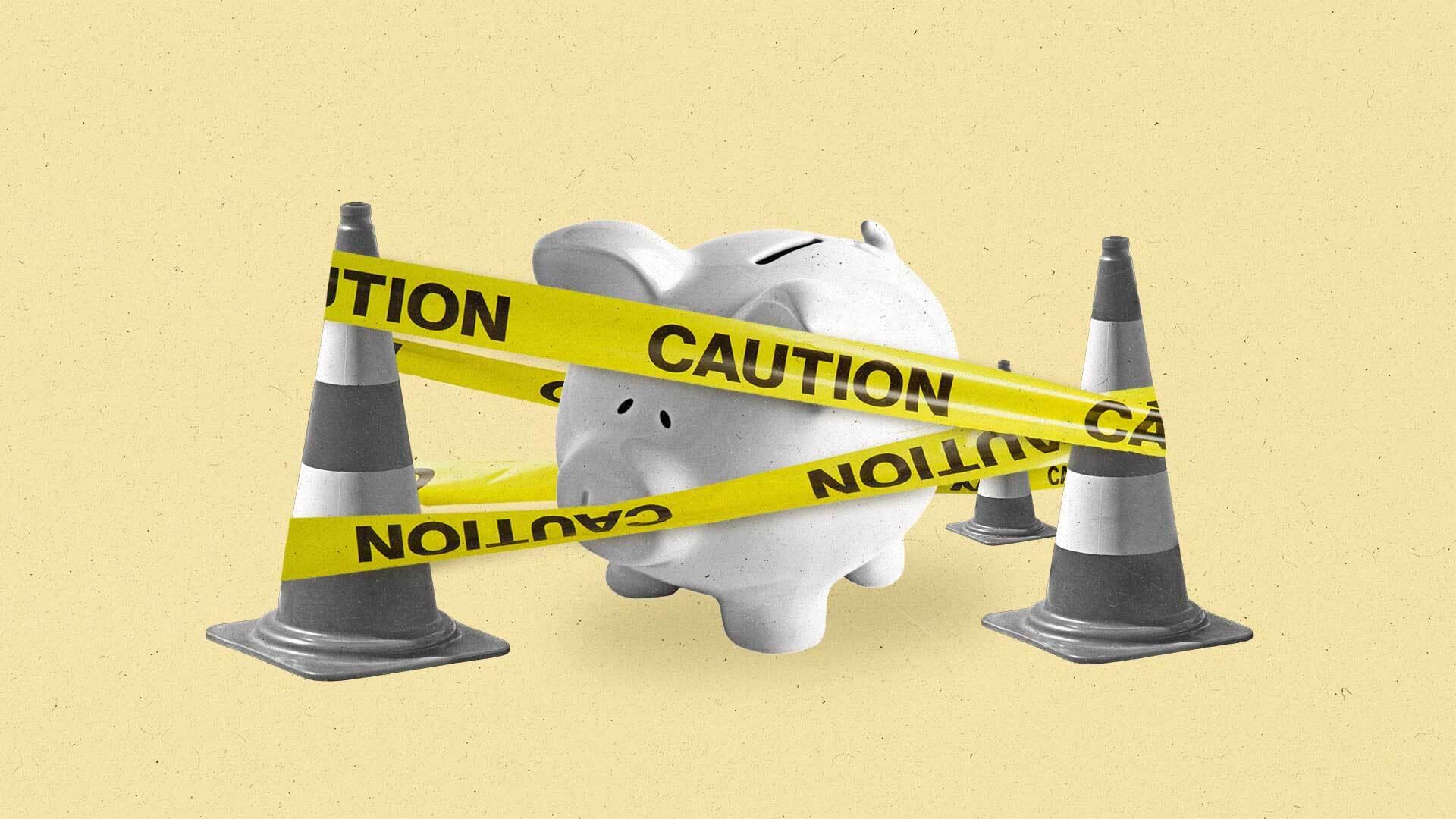 A piggy bank surrounded by traffic cones and caution tape.