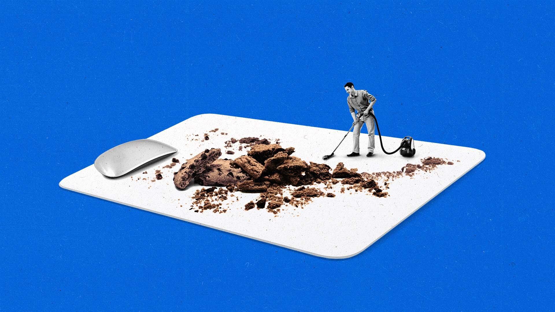 Man stands vacuums cookie crumbs while standing on a mouse pad with a mouse nearby.