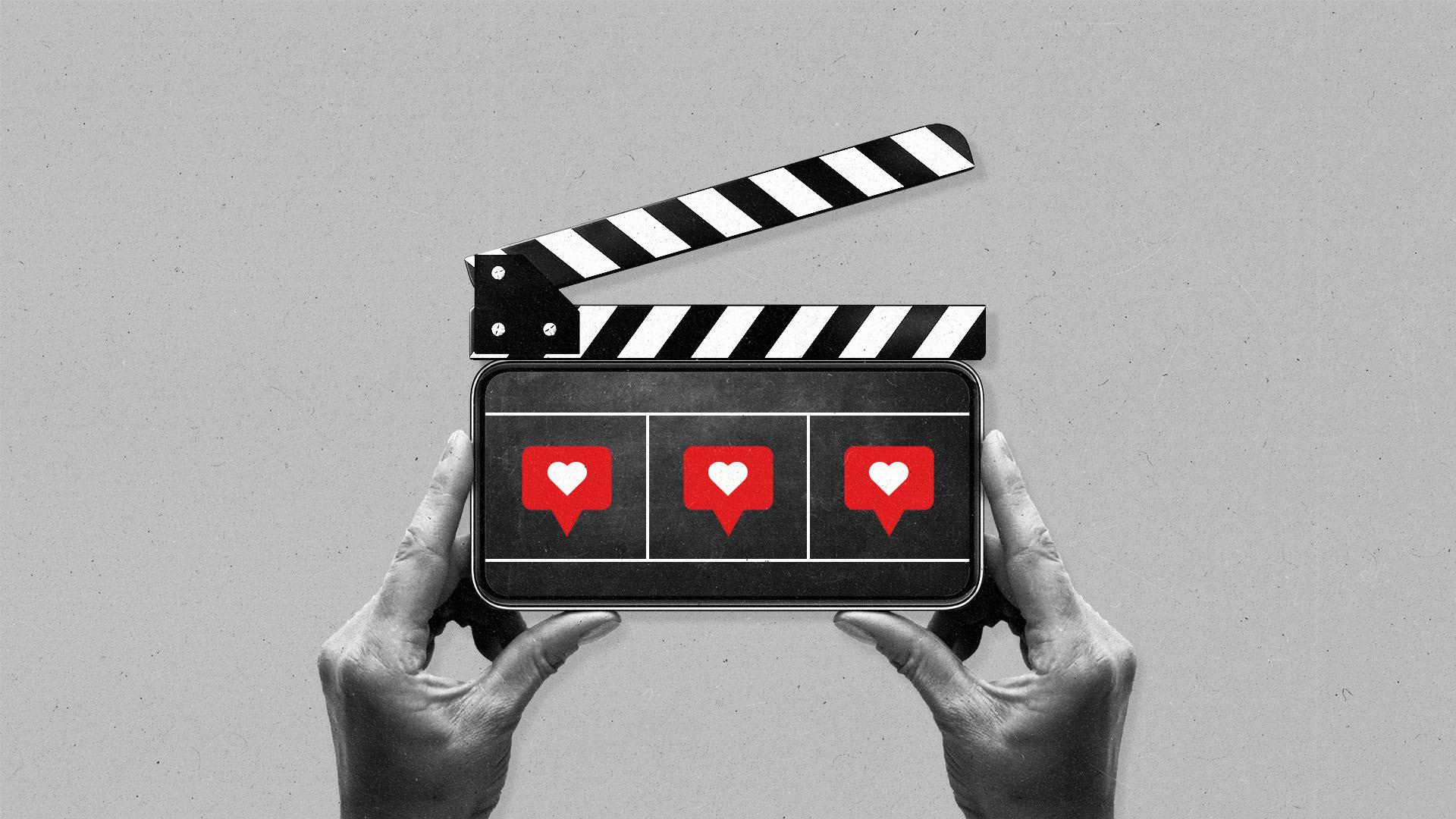 Two hands hold a smartphone vertically with three "like" social media icons and a clapboard on top.
