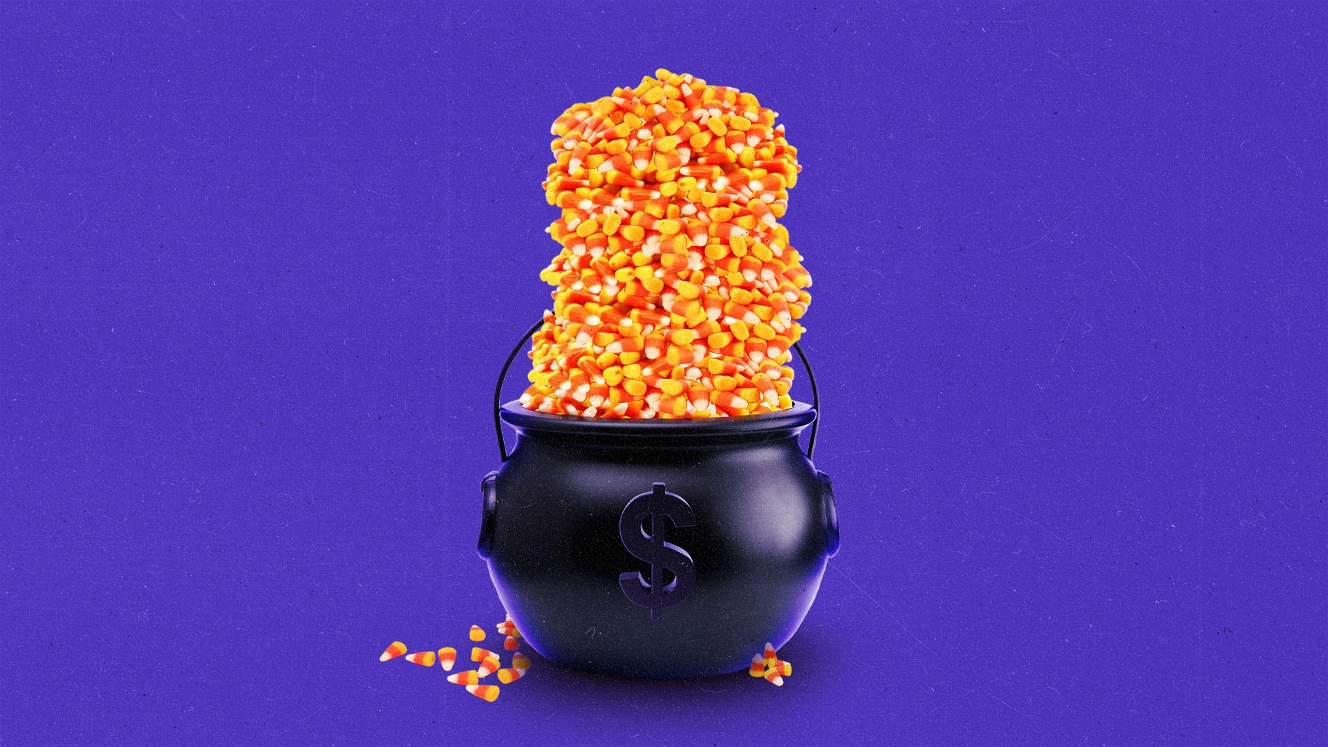 A cauldron shaped candy bucket filled with an overflowing stack of candy corn.