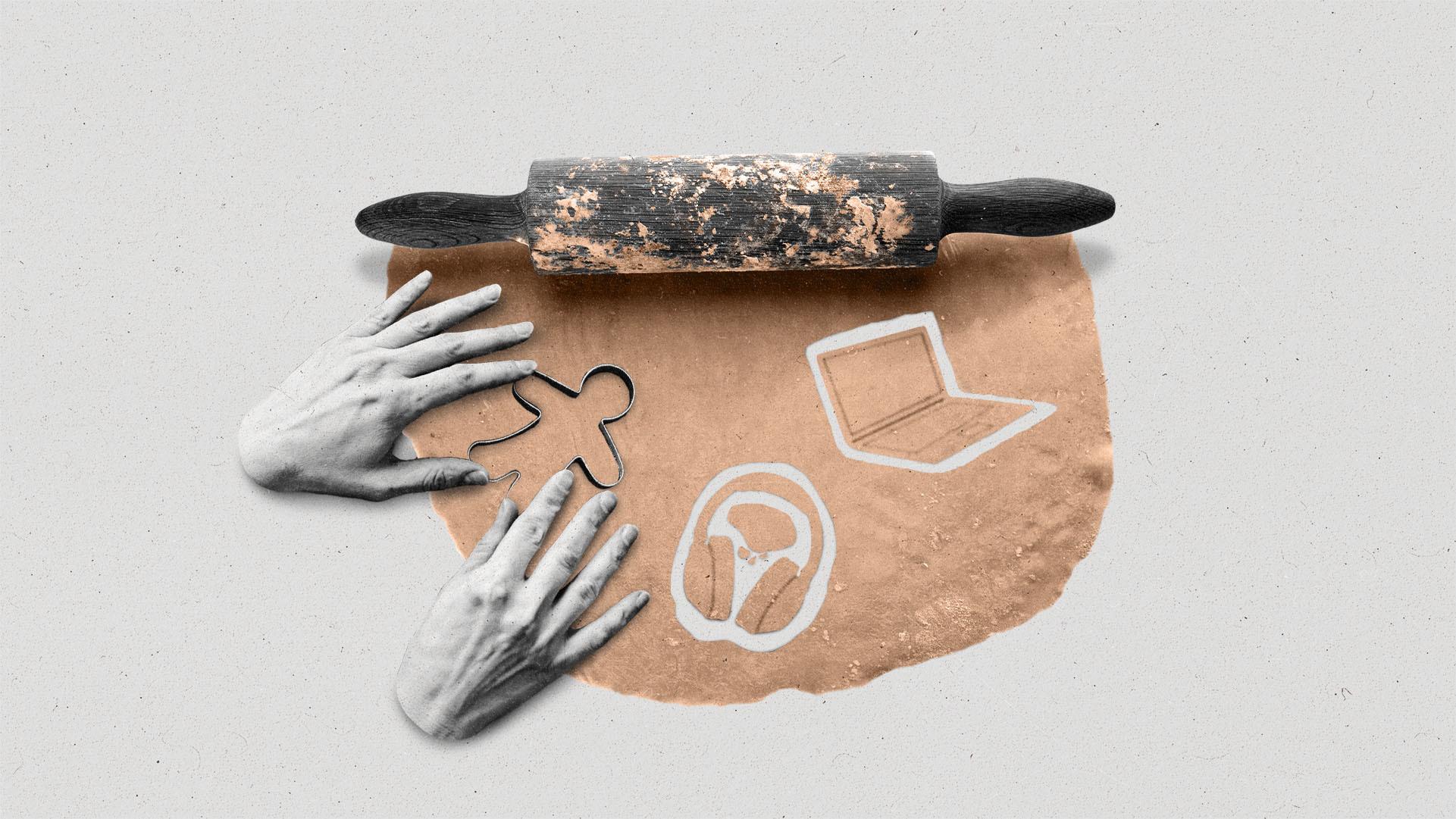 Two hands pressing cookie cutters into rolled out dough, with laptop and headphone shapes already cut out.