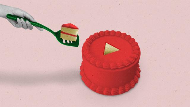 Hand taking a play button-shaped slice of cake out of a red cake using a green spatula.