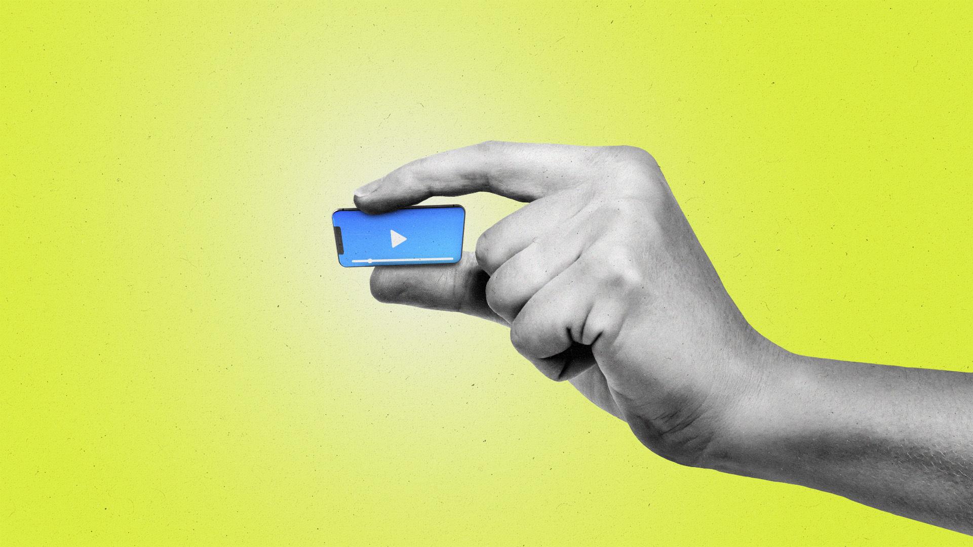 Hand pinching a miniature smartphone that's playing video content.