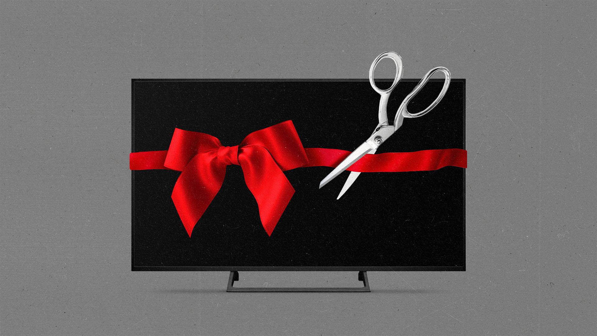 A TV with a red ribbon around it being cut.