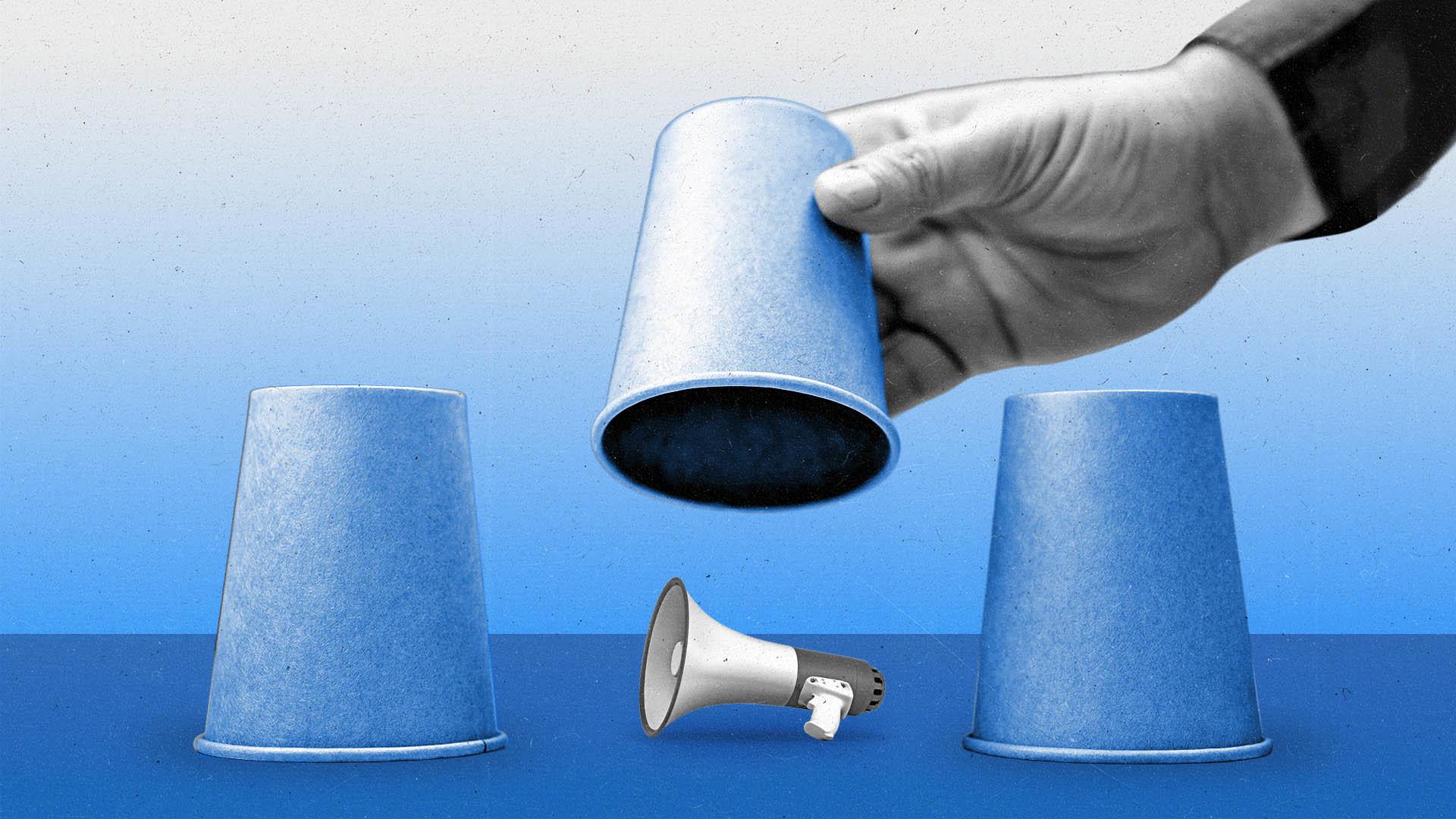 3 cups upside down on a surface, with a hand lifting the middle one to reveal a megaphone.